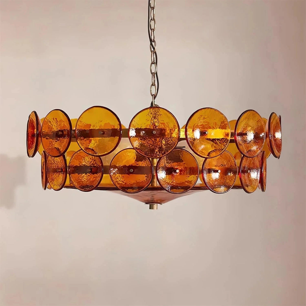 Joltly amber glass disc chandelier hanging against a plain beige wall