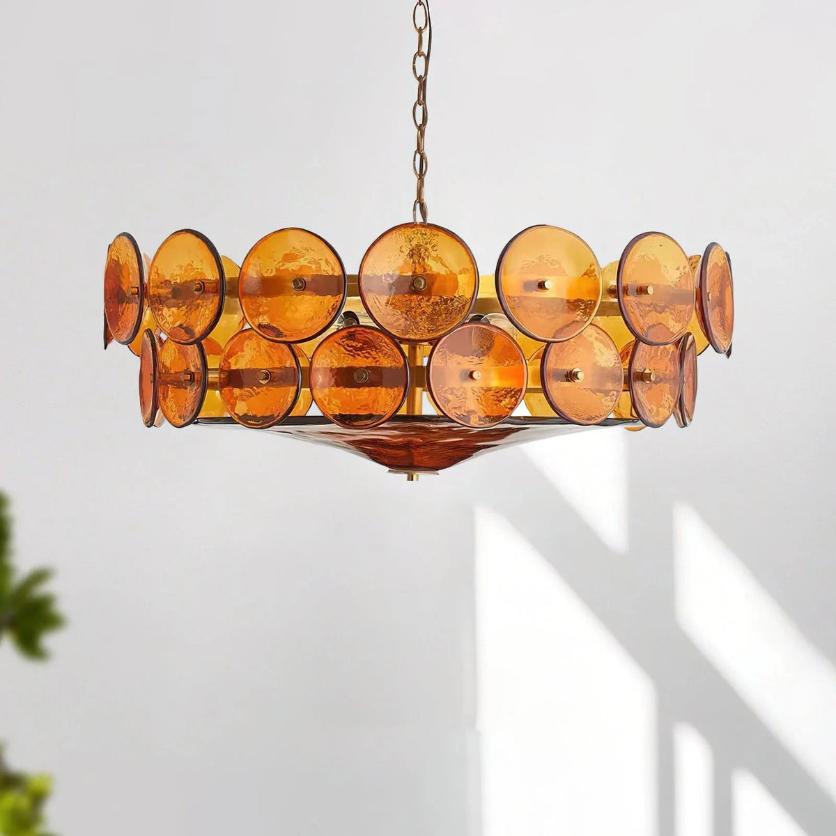 Joltly amber glass disc chandelier hanging against a plain white wall