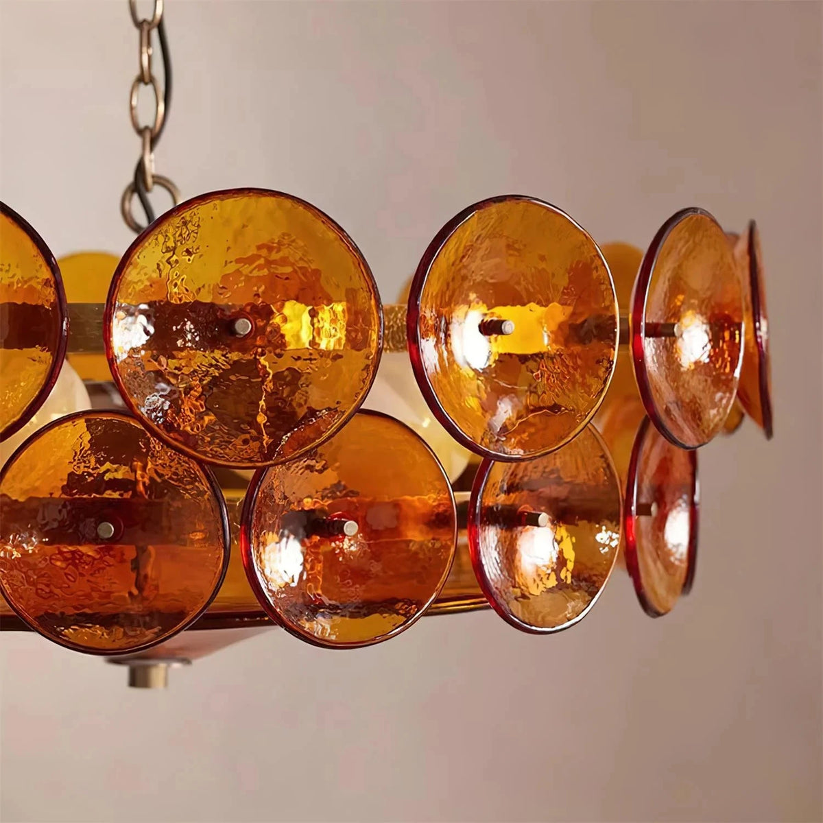 Side close-up of the Joltly amber glass disc chandelier showing textured glass discs and the hanging chain