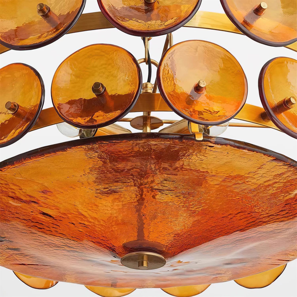 Close-up of the glass bowl and amber glass discs of the Joltly chandelier seen from below