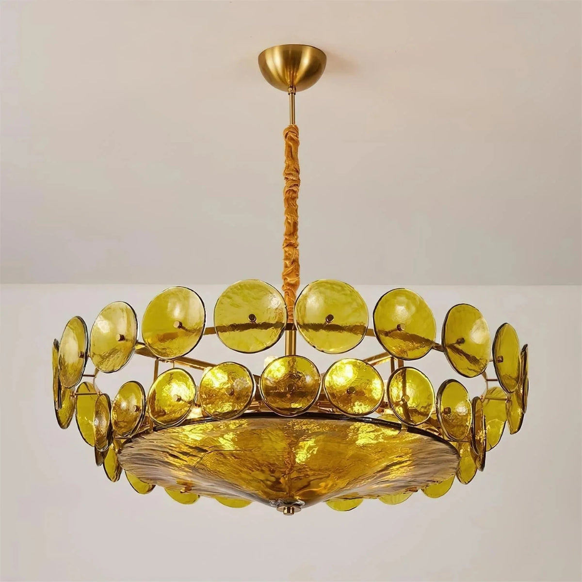 Joltly green glass disc chandelier hanging from a gold-finish ceiling canopy against a plain grey wall