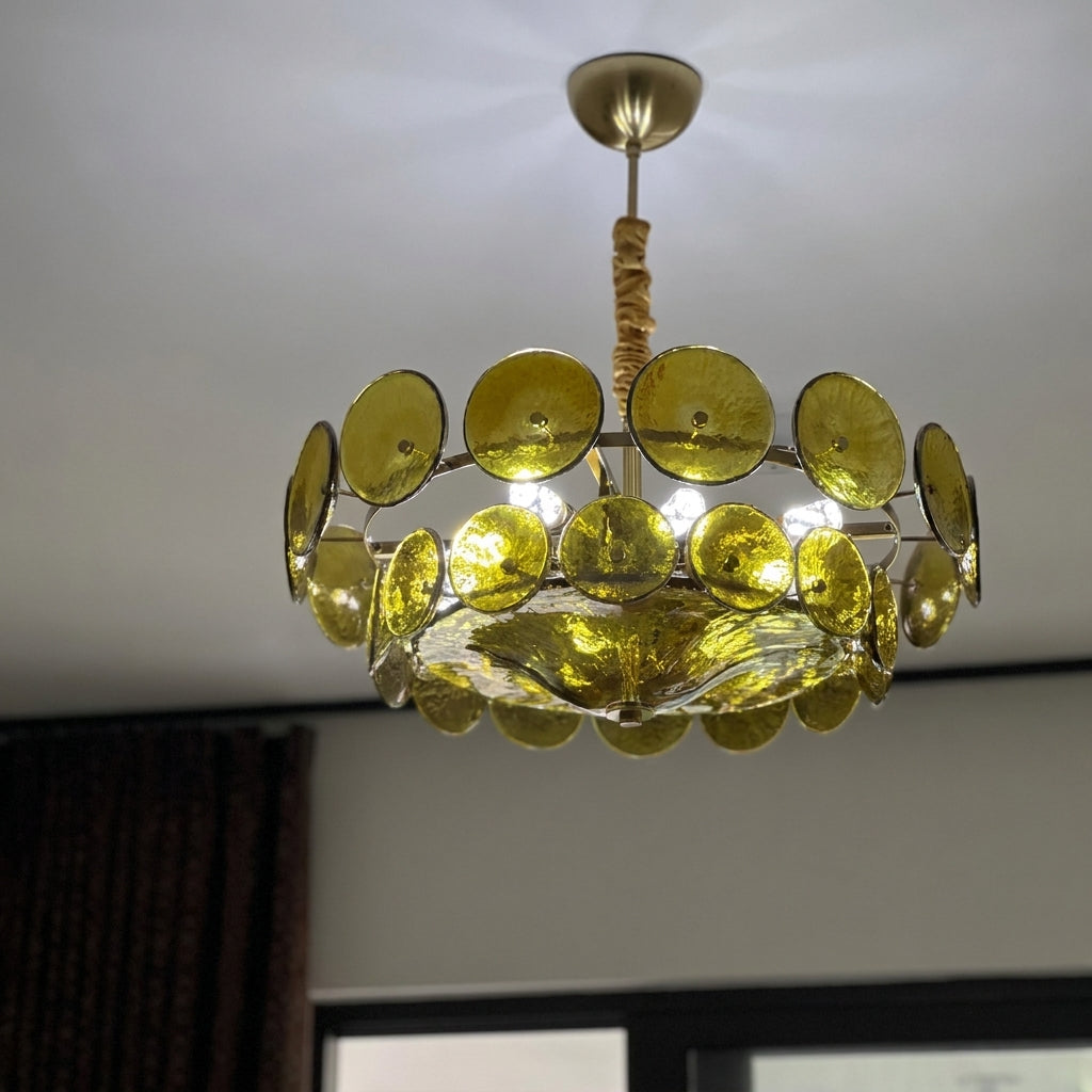 Joltly green glass disc chandelier lit, hanging from a ceiling canopy