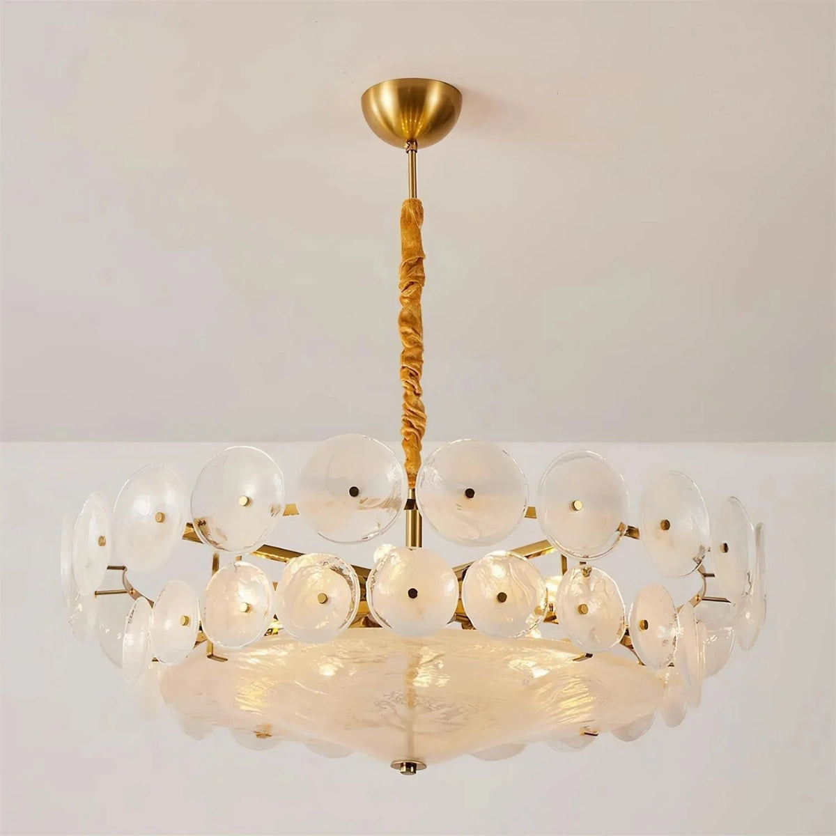 Joltly white frosted glass disc chandelier hanging from a gold-finish ceiling canopy against a plain wall