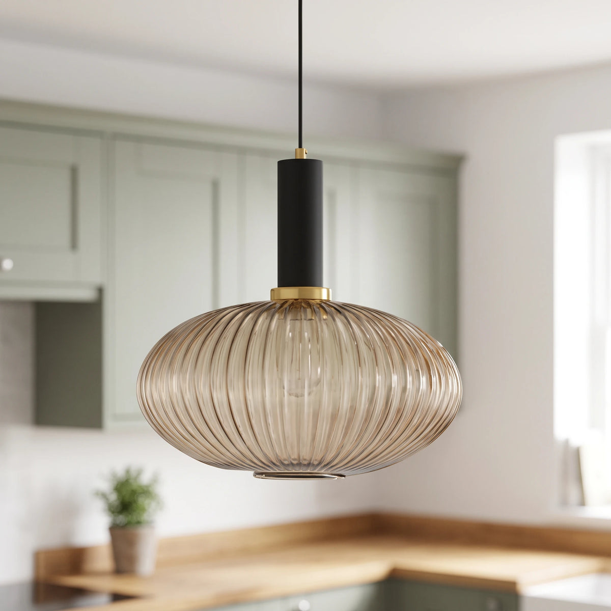 Kael wide champagne ribbed glass pendant light with a black cap in front of sage green kitchen cabinets