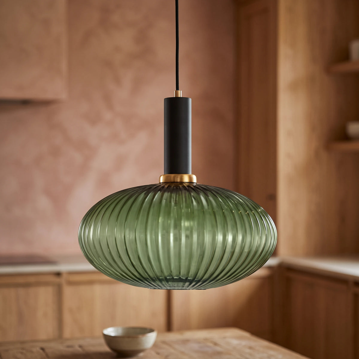 Kael wide green ribbed glass pendant light with a black cap against a terracotta clay kitchen wall and oak joinery