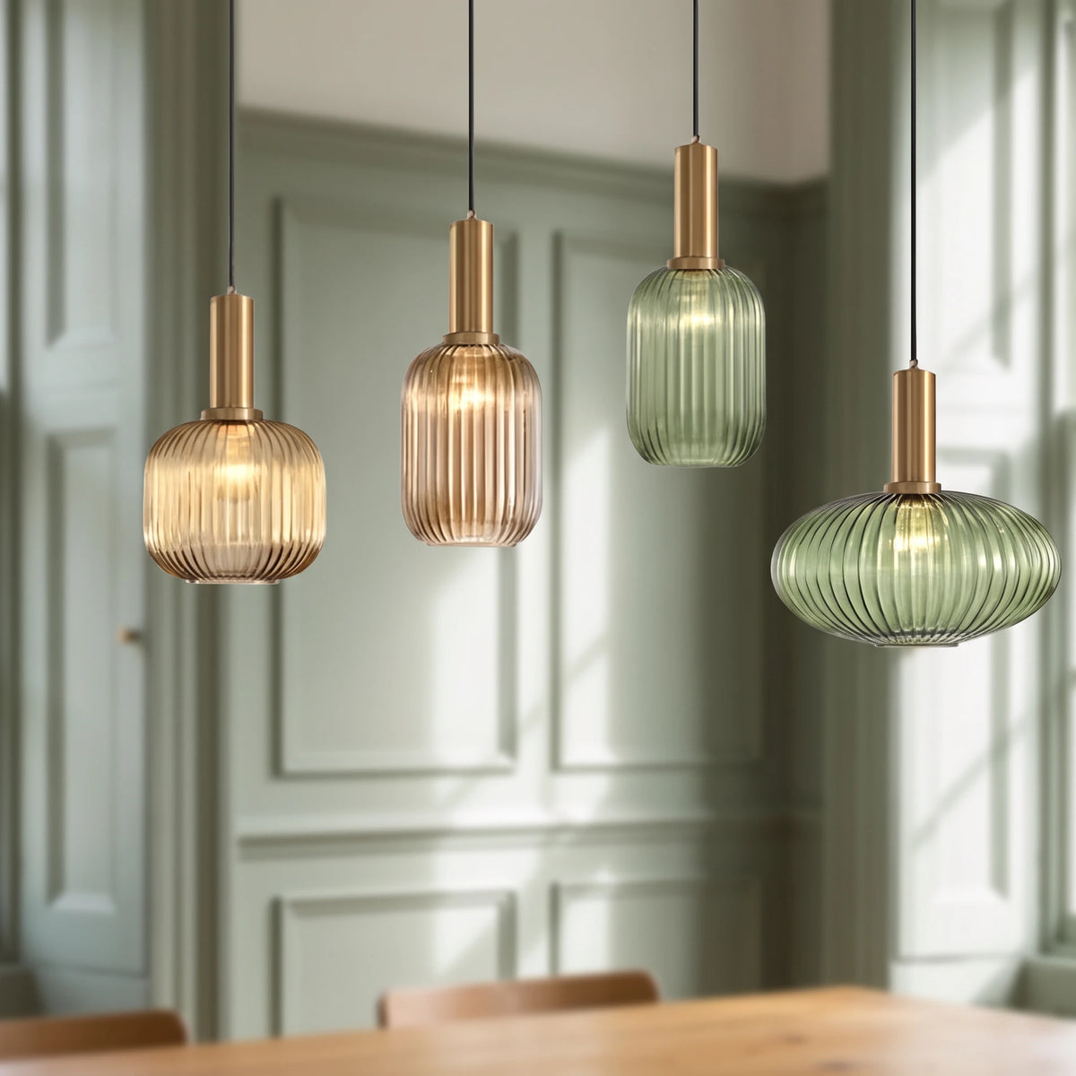 4 Kael ribbed glass pendant lights in champagne, amber and green with brass caps above a wooden table in a sage green panelled dining nook