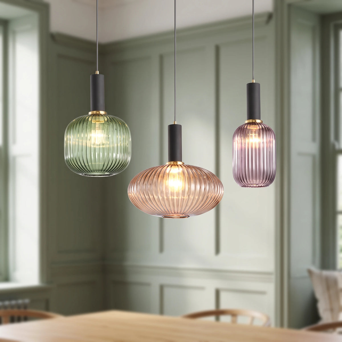 3 Kael ribbed glass pendant lights in green, amber and smoked purple with black caps in a sage green panelled dining nook