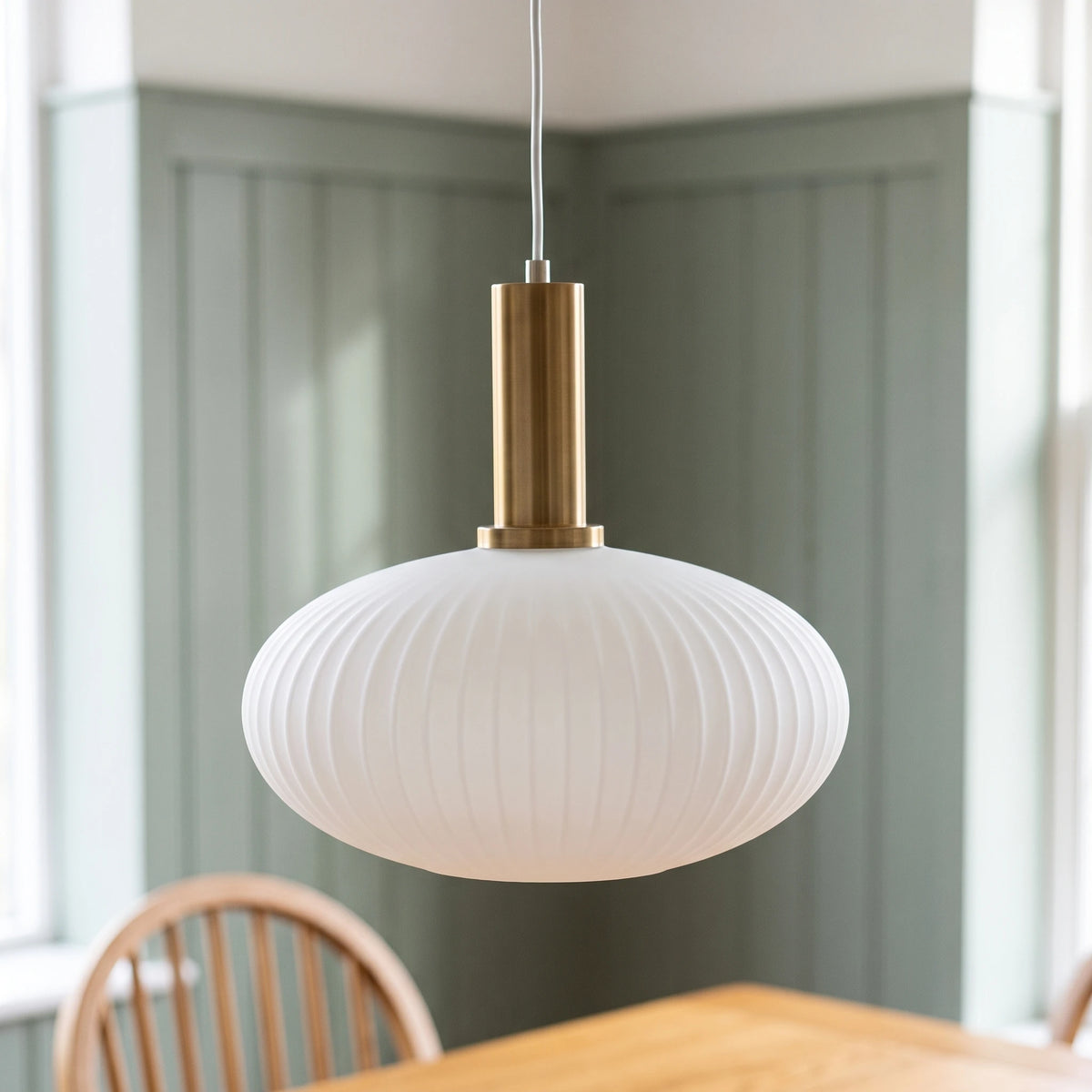 Kael wide white opal ribbed glass pendant light with a brass cap against a sage green panelled dining nook wall