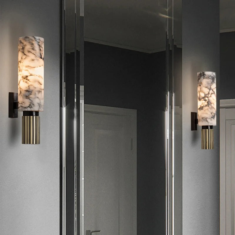Marble cylinder kopu wall sconce casting a soft ambient glow in a contemporary mirrored hallway
