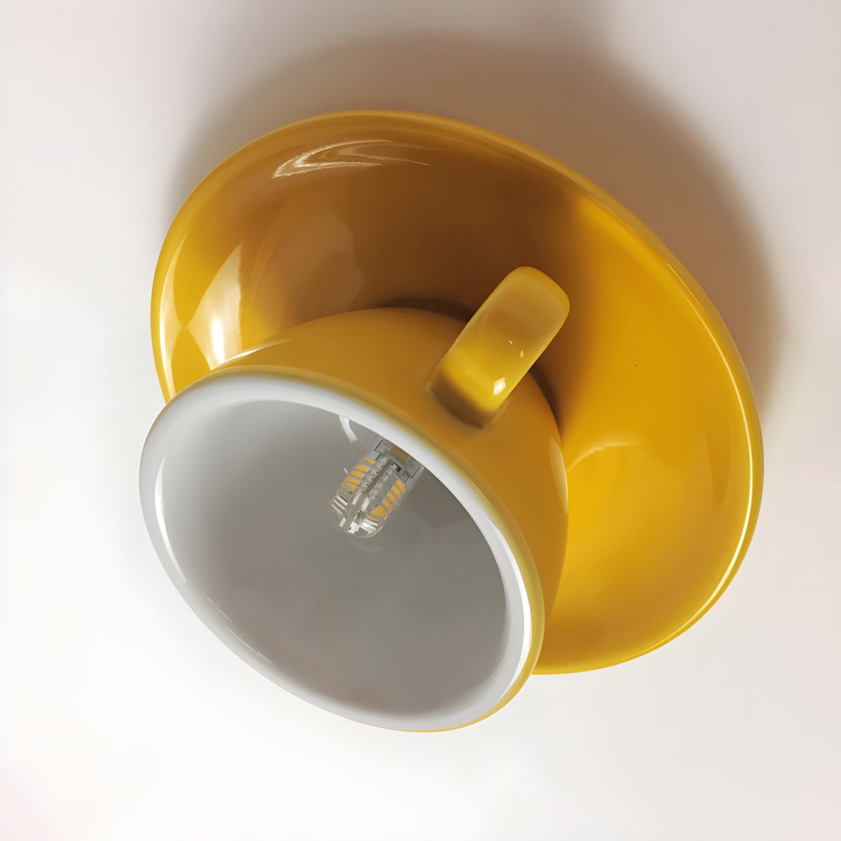 Angled close-up of the yellow kupce teacup light interior showing the premium ceramic glaze and G4 LED bulb