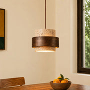 Single kyra Japandi travertine stone pendant light with a dark wood band hanging over a dining table