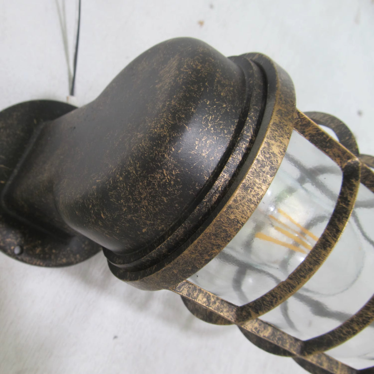 Close-up of the Laze rust bronze bulkhead wall light arm and distressed finish