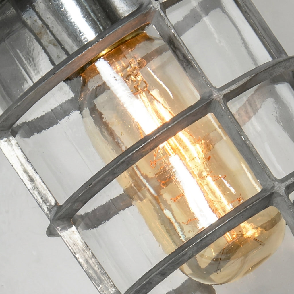 Close-up of the Laze silver bulkhead wall light cage and clear glass