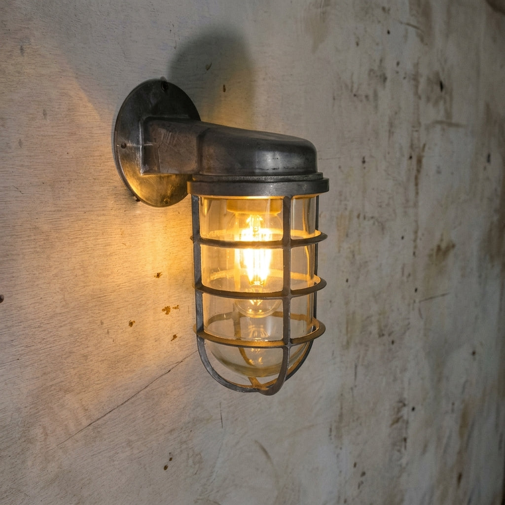 Laze silver cage guard bulkhead wall light lit on a weathered plaster wall