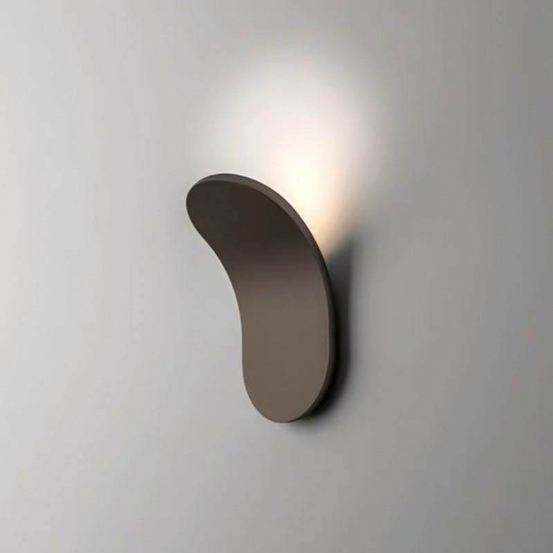 Close-up of a brown lexi Nordic shield wall lamp casting a warm ambient glow on a plain wall