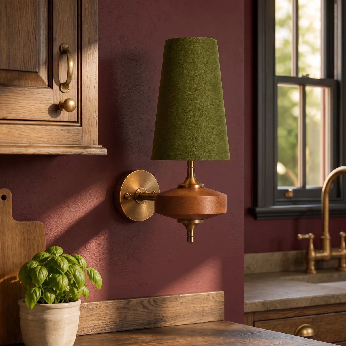 Lisk green fabric shade wall light on an oxblood kitchen wall beside a sash window and a pot of basil