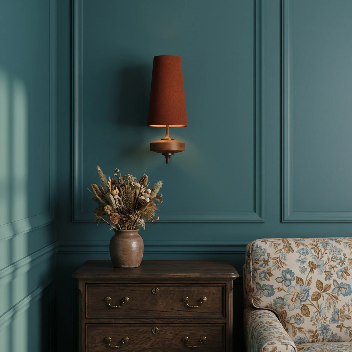 Lisk red fabric shade wall light on a deep teal panelled wall above an oak chest of drawers with dried flowers