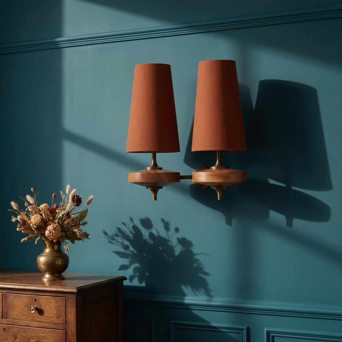 Lisk red 2-head fabric shade wall light on a deep teal wall above a small oak chest with dried flowers