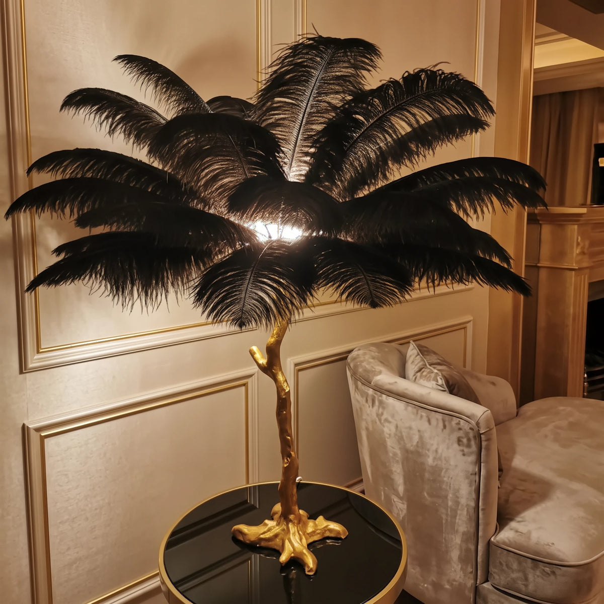 Close-up of the Lorne black ostrich feather lamp glowing against a champagne panelled wall