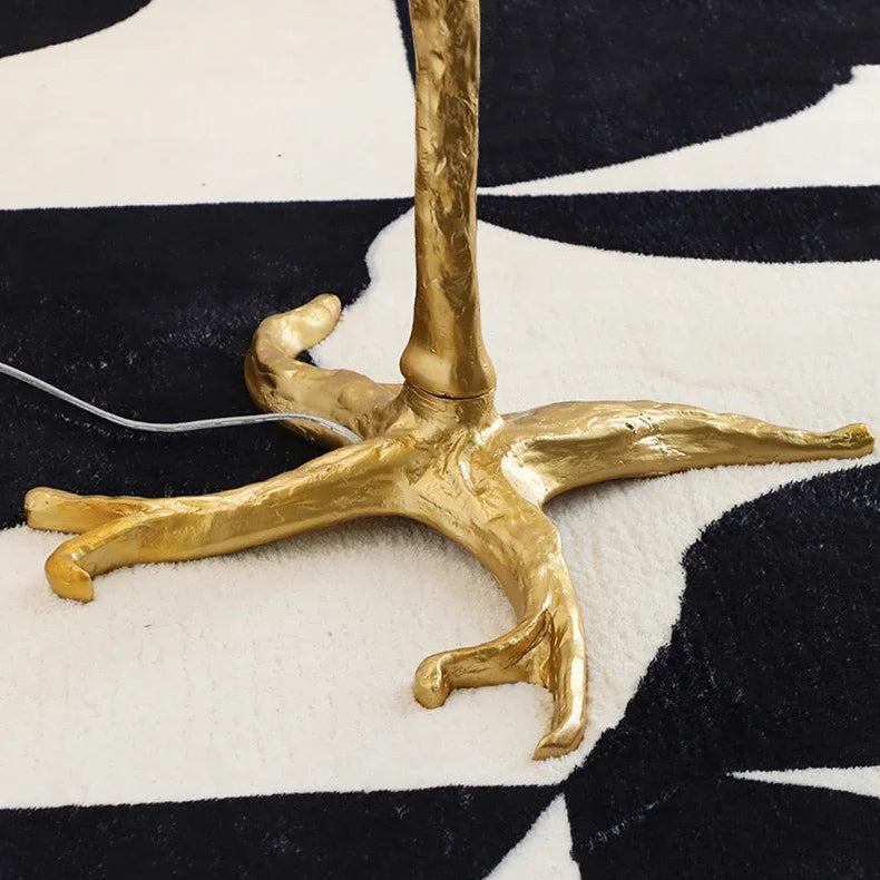Close-up of the Lorne gold branch base with claw-style feet and a white cable on a black and cream rug
