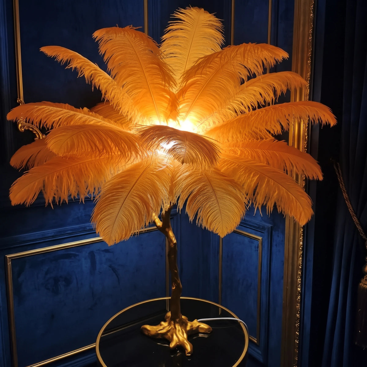 Close-up of the Lorne orange ostrich feather lamp glowing against a navy velvet wall