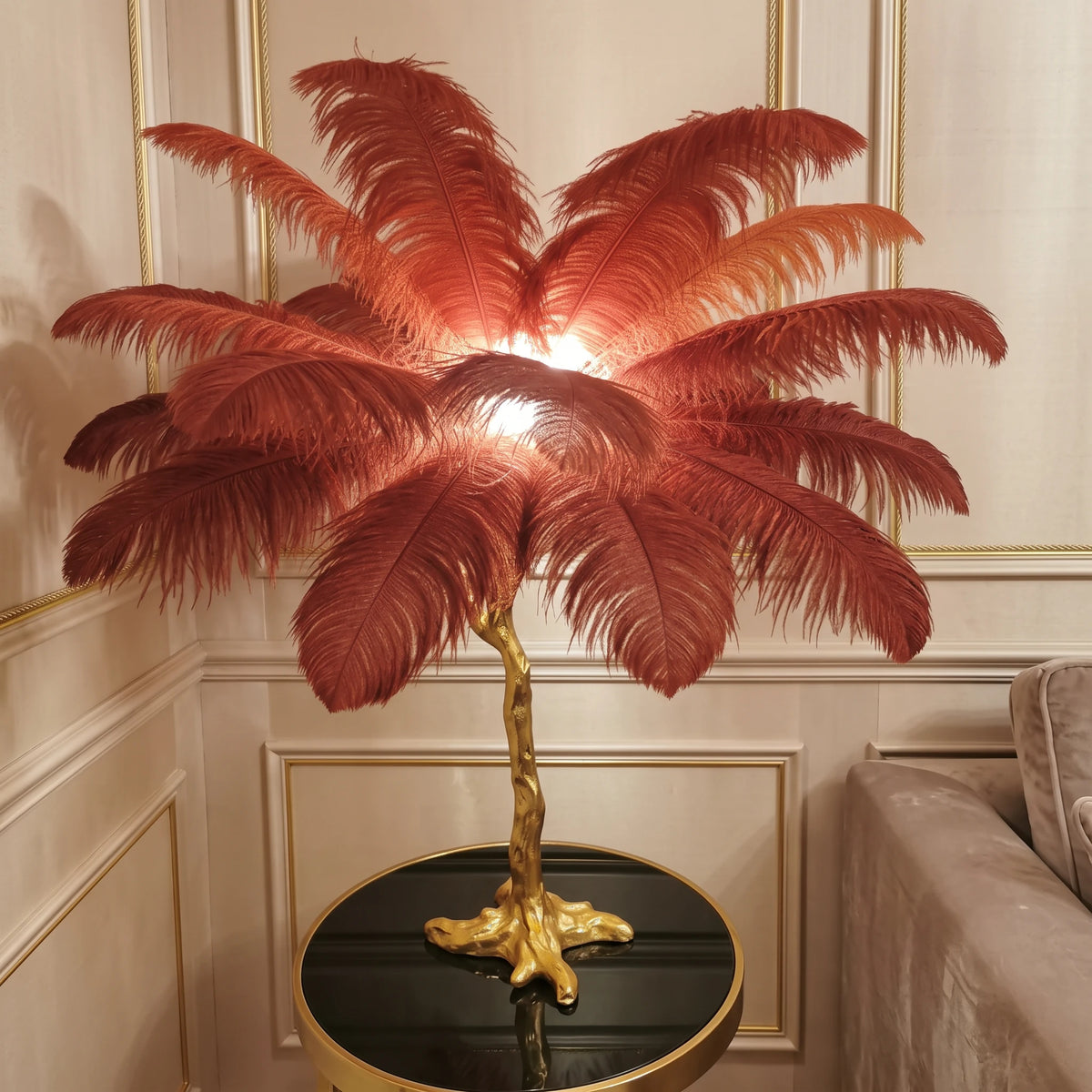 Close-up of the Lorne red ostrich feather lamp glowing against a champagne panelled wall
