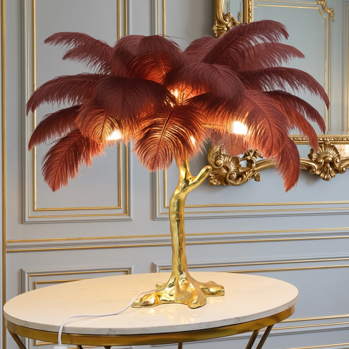 Lorne red ostrich feather lamp with a gold branch base on a marble side table against a dove grey panelled wall