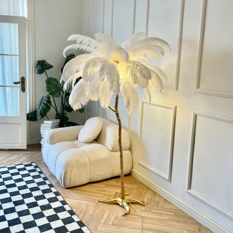 Lorne white ostrich feather floor lamp in a living room corner beside a cream armchair and a monstera plant