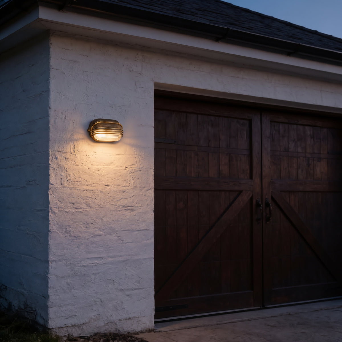 Lude bulkhead wall light lit on a white garage wall beside dark timber doors