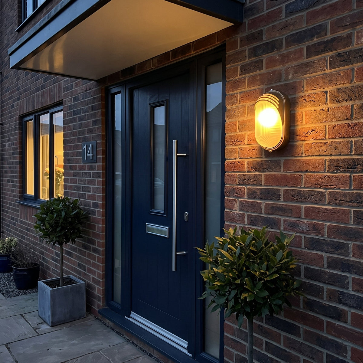 Lude bulkhead wall light lit beside a navy front door under a porch canopy in the evening