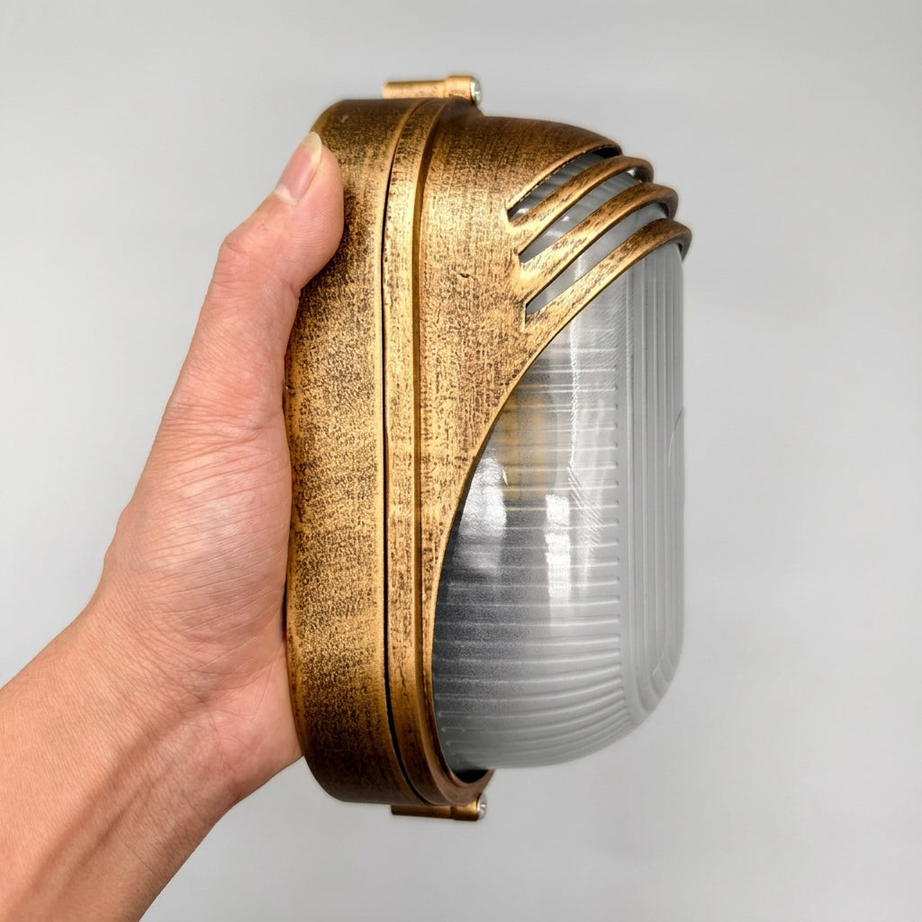 Hand holding the Lude louvred hood bulkhead wall light showing its hood and glass shade