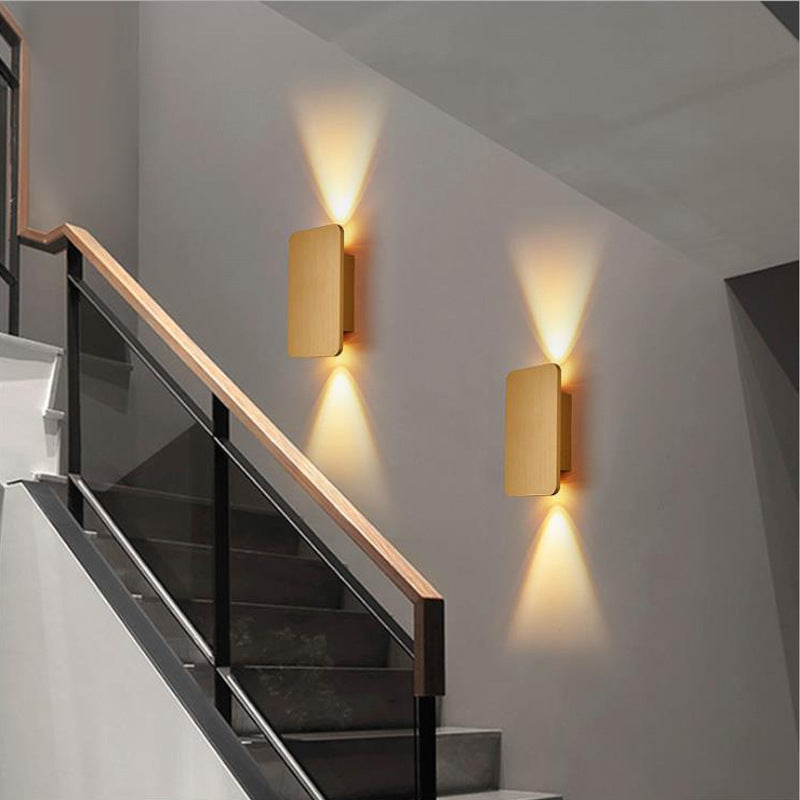 Pair of gold flat panel mazka LED sconces illuminating a contemporary indoor staircase