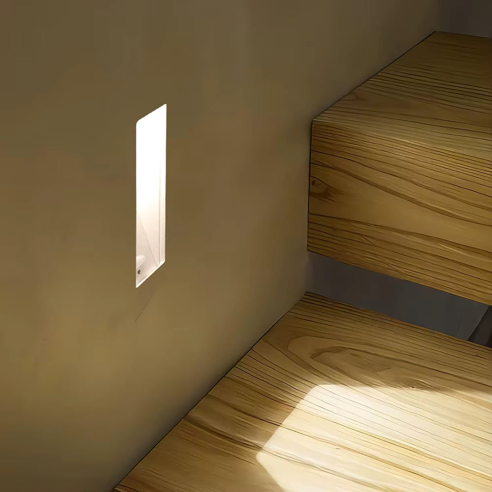 Melte long strip recessed LED wall light glowing beside wooden stairs