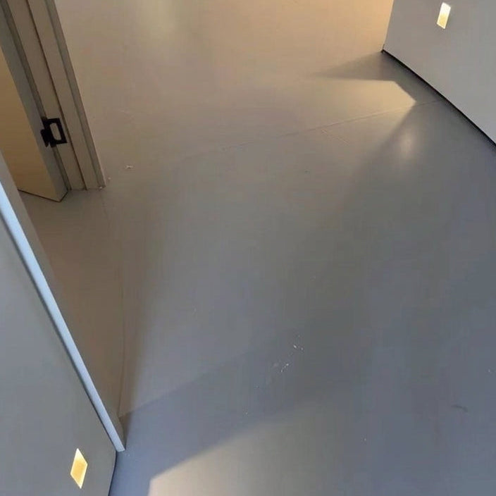 Melte recessed LED wall light casting a soft glow across a concrete floor