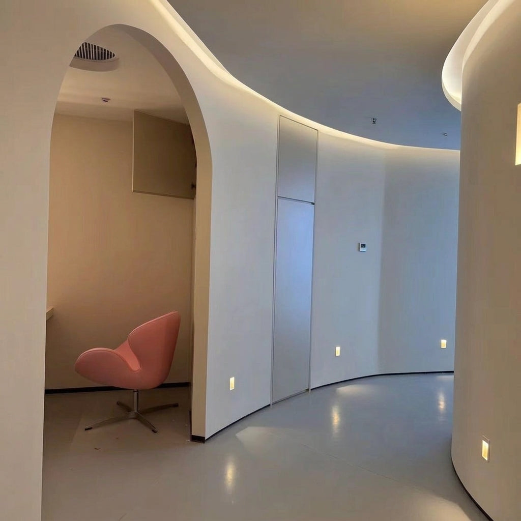 Melte recessed LED wall lights along a curved corridor with a pink armchair