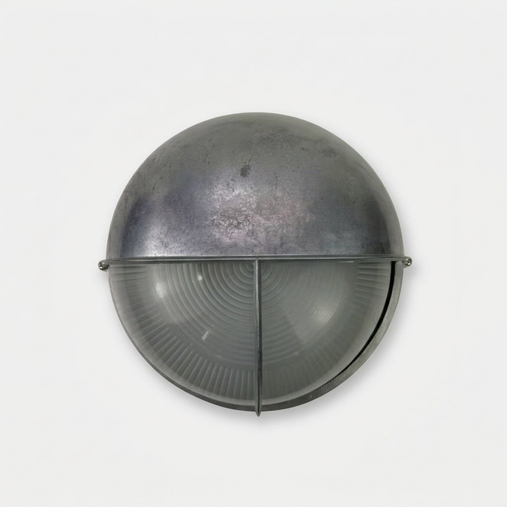 A vintage industrial dome-shaped wall light fixture with a textured metallic upper dome and a ribbed translucent lower lens, shown against a plain light grey background.