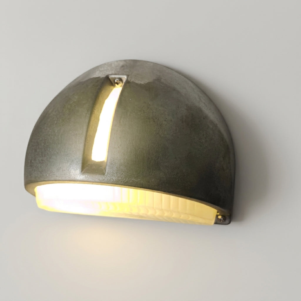 A modern semi circle wall light with a textured dark grey metal finish, emitting a warm yellow light from the bottom and centre.