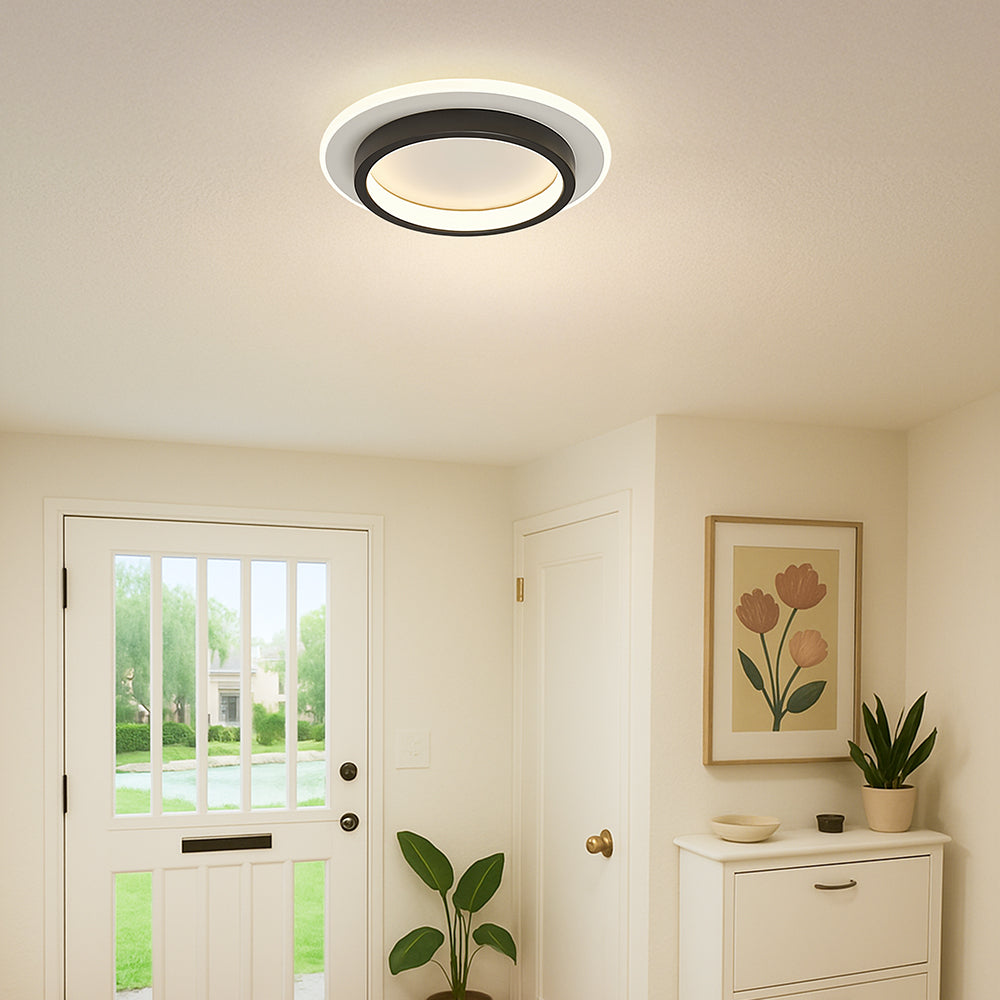 Modern black halo LED mura ceiling light installed in a bright entryway with a white door