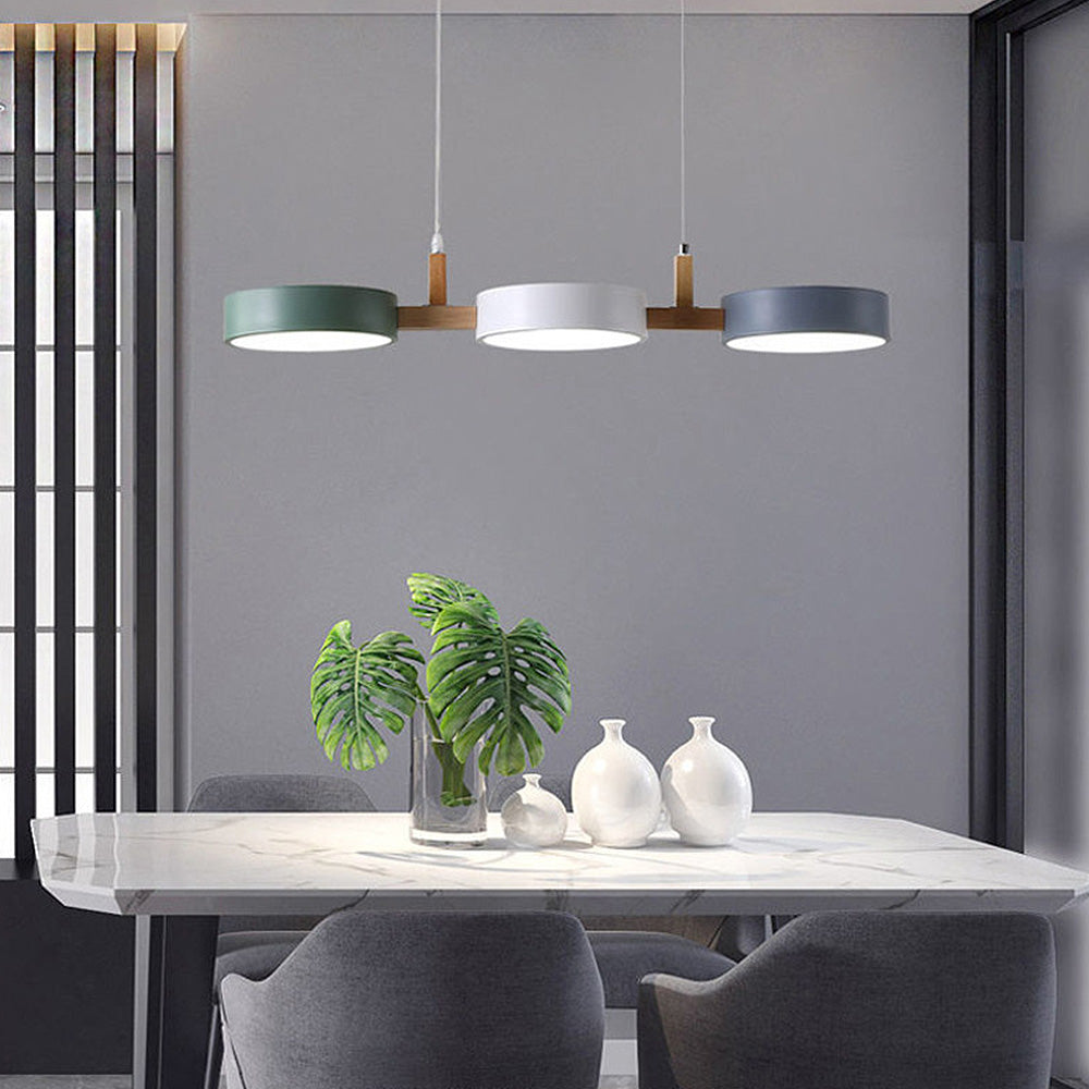 Green, white, and grey linear nohit pendant casting a warm glow over a minimalist dining table