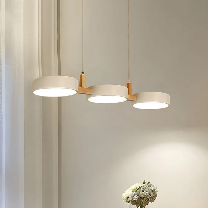 Solid white 3-head drum nohit pendant light providing ambient light over a round dining table