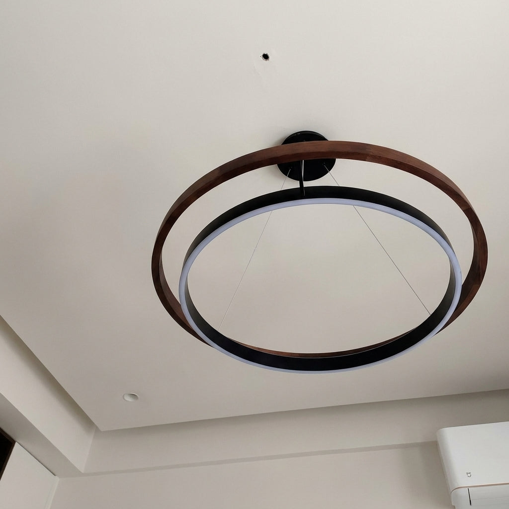 Angled view of the Nyles two-ring wood-grain LED chandelier on a white ceiling