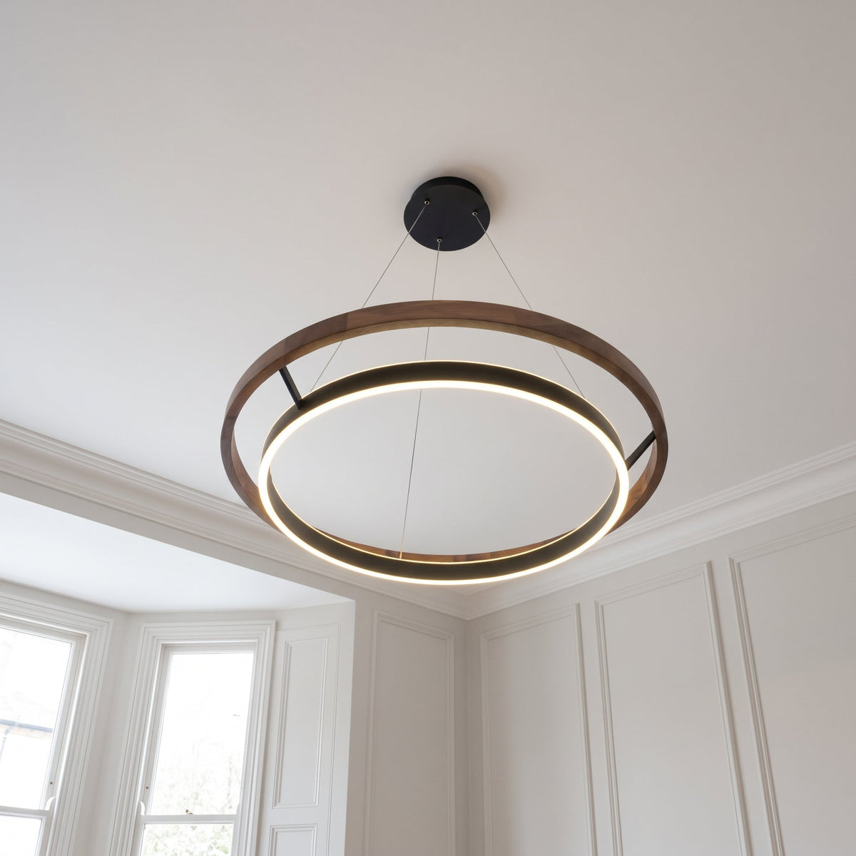 Nyles two-ring wood-grain LED chandelier mounted on a white ceiling in a panelled room