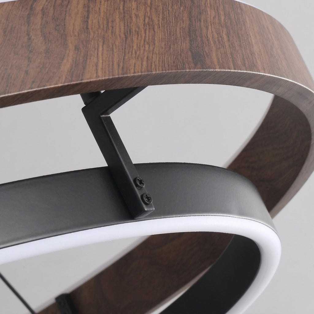 Close-up of the Nyles chandelier bracket joining the wood-grain outer ring and black inner ring