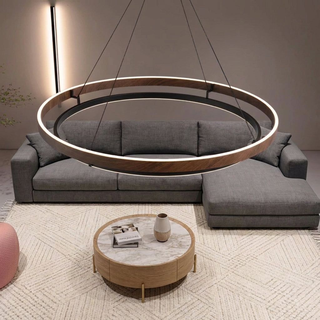 Nyles wood-grain two-ring LED chandelier hanging above a grey sectional sofa and marble coffee table