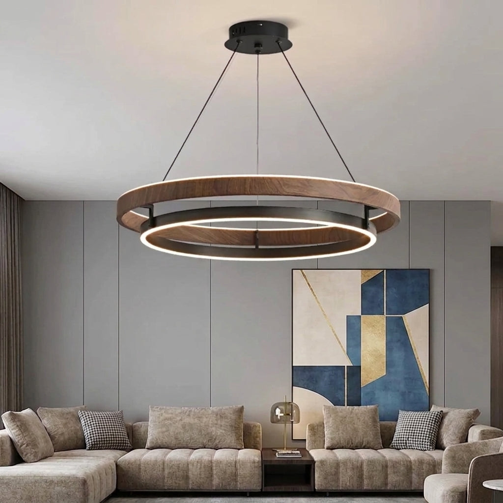 Nyles wood-grain two-ring LED chandelier hanging above a taupe sectional sofa in a living room with abstract wall art