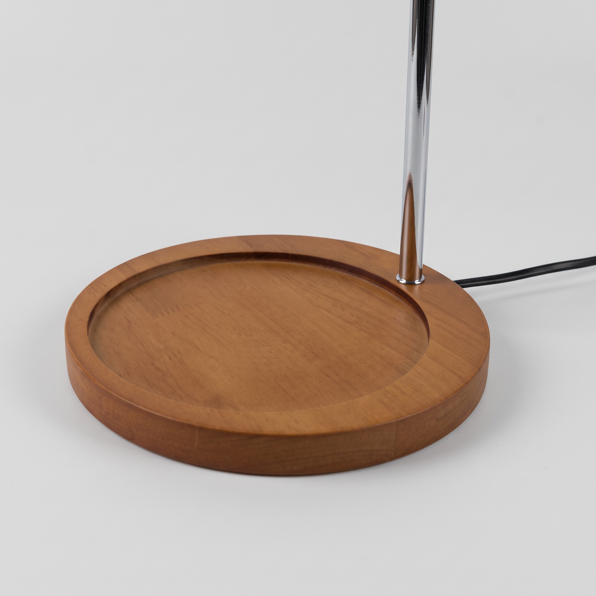Close-up of the Ondo candle warmer lamp round wooden base and chrome arm on a light grey background