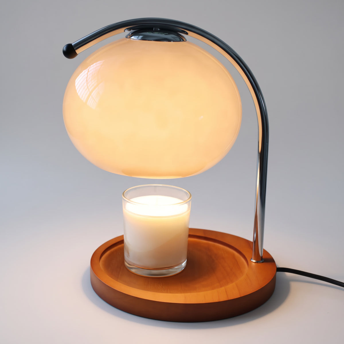 Ondo milky white glass dome candle warmer lamp with a chrome arm and wooden base on a plain light grey background