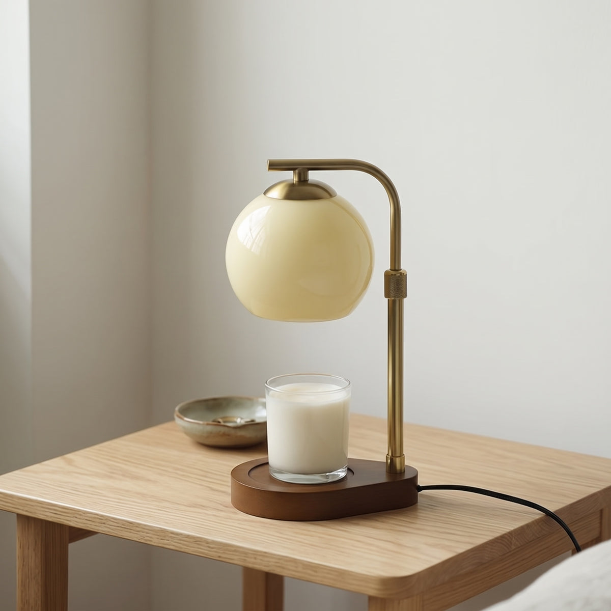 Orsa beige glass globe candle warmer lamp with a dark wooden base on an oak side table