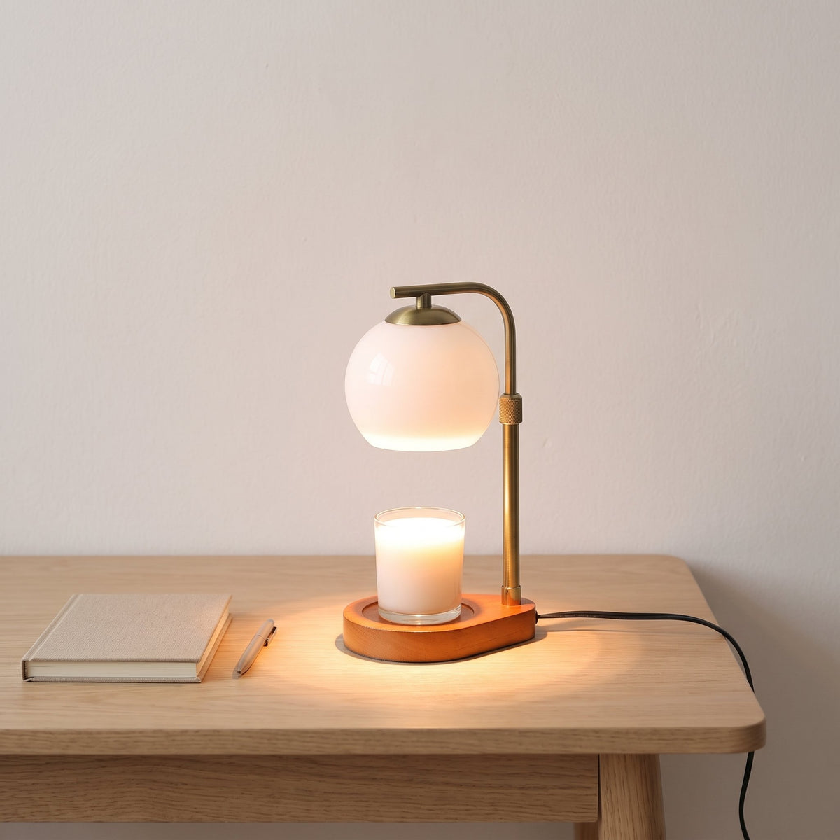 Orsa glass globe candle warmer lamp on an oak desk beside a notebook