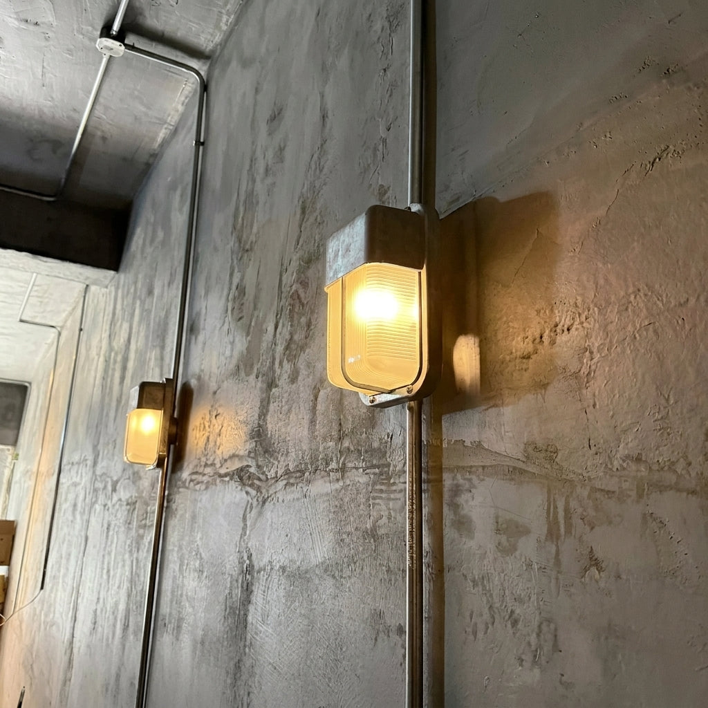 Ostin silver bulkhead wall lights glowing along a concrete corridor wall